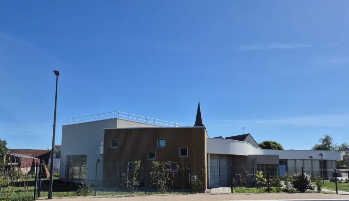 Le pignon du périscolaire habillé de bois vertical, prolongé par le volume blanc de l'accueil.