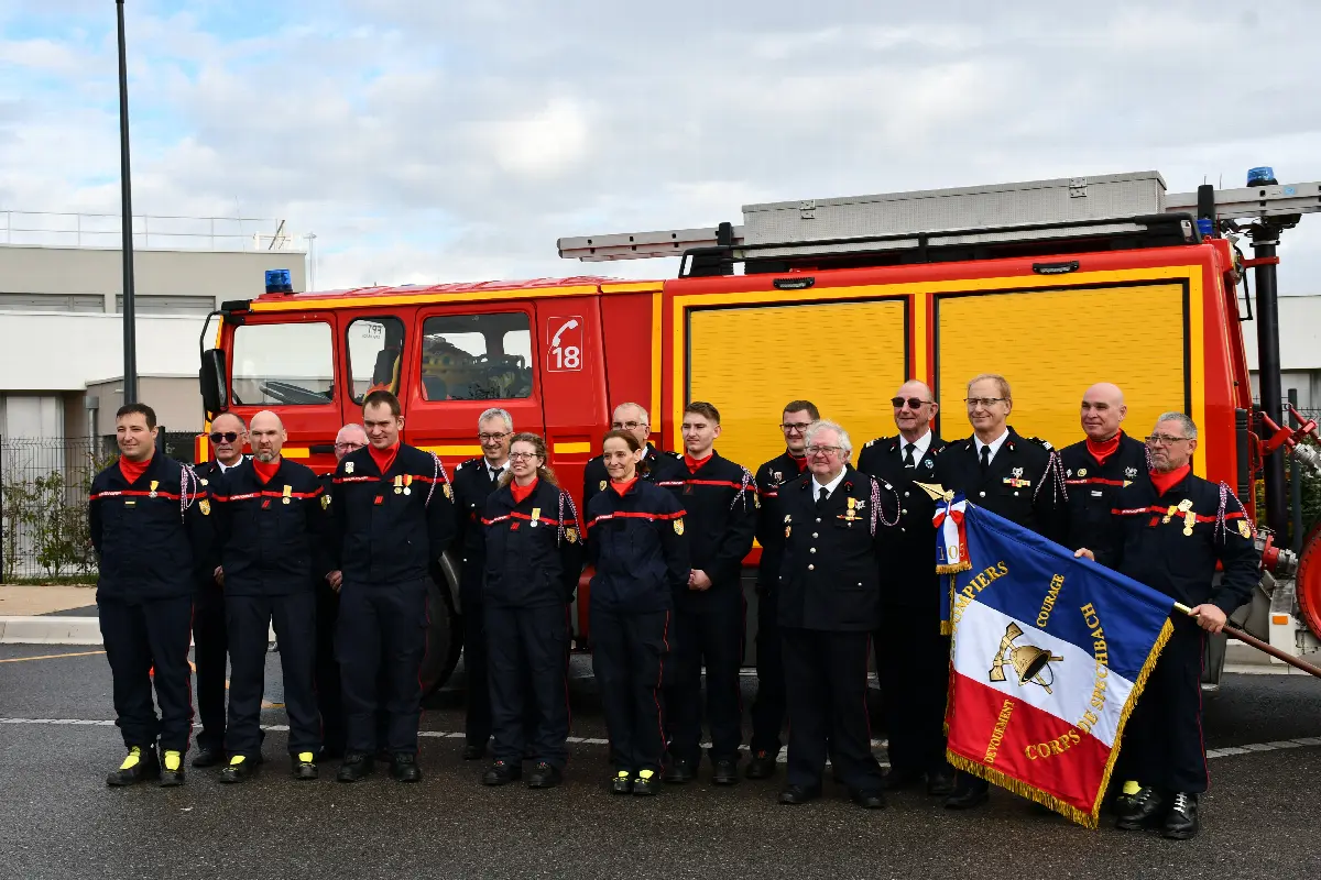 Le corps des sapeurs-pompiers de Spechbach en uniforme, rassemblé devant un camion de secours avec le drapeau du corps