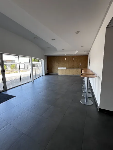 Espace bar de la salle rouge avec comptoir en bois clair, alignement de tabourets hauts et baies vitrées donnant sur la terrasse.