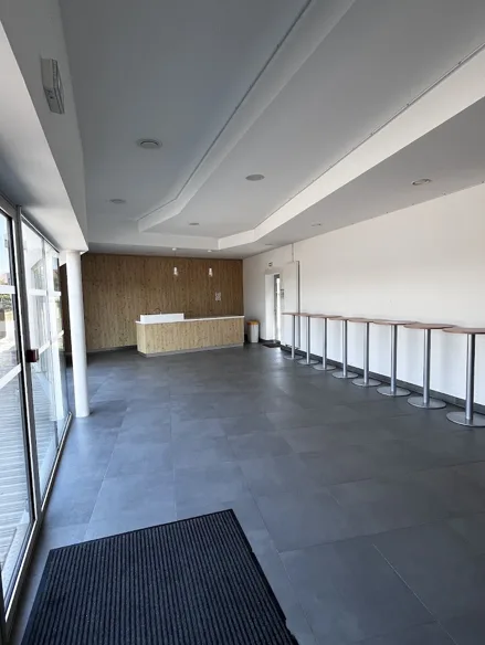 Bar de la salle rouge vu depuis l'entrée, comptoir en bois clair adossé à un mur habillé de lattes et mange-debout alignés le long du mur.